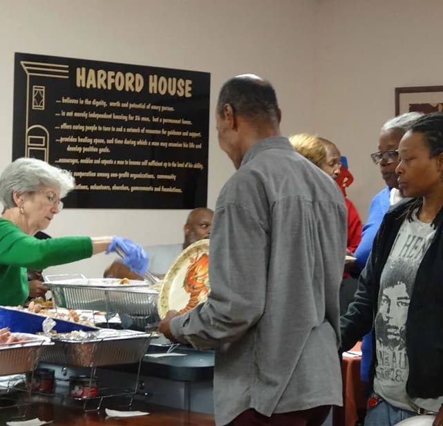 A group of people standing around serving food.