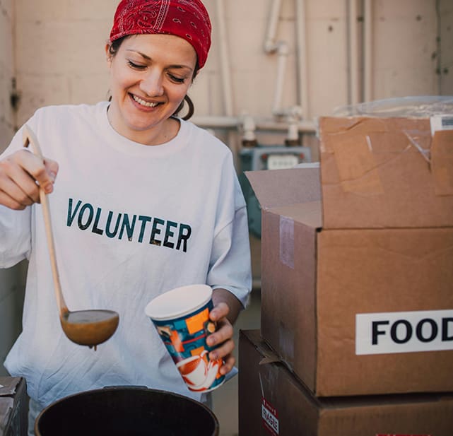 A woman in white shirt holding cup near brown box.