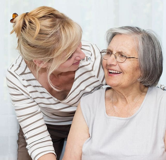 A woman is petting an older lady 's shoulder.