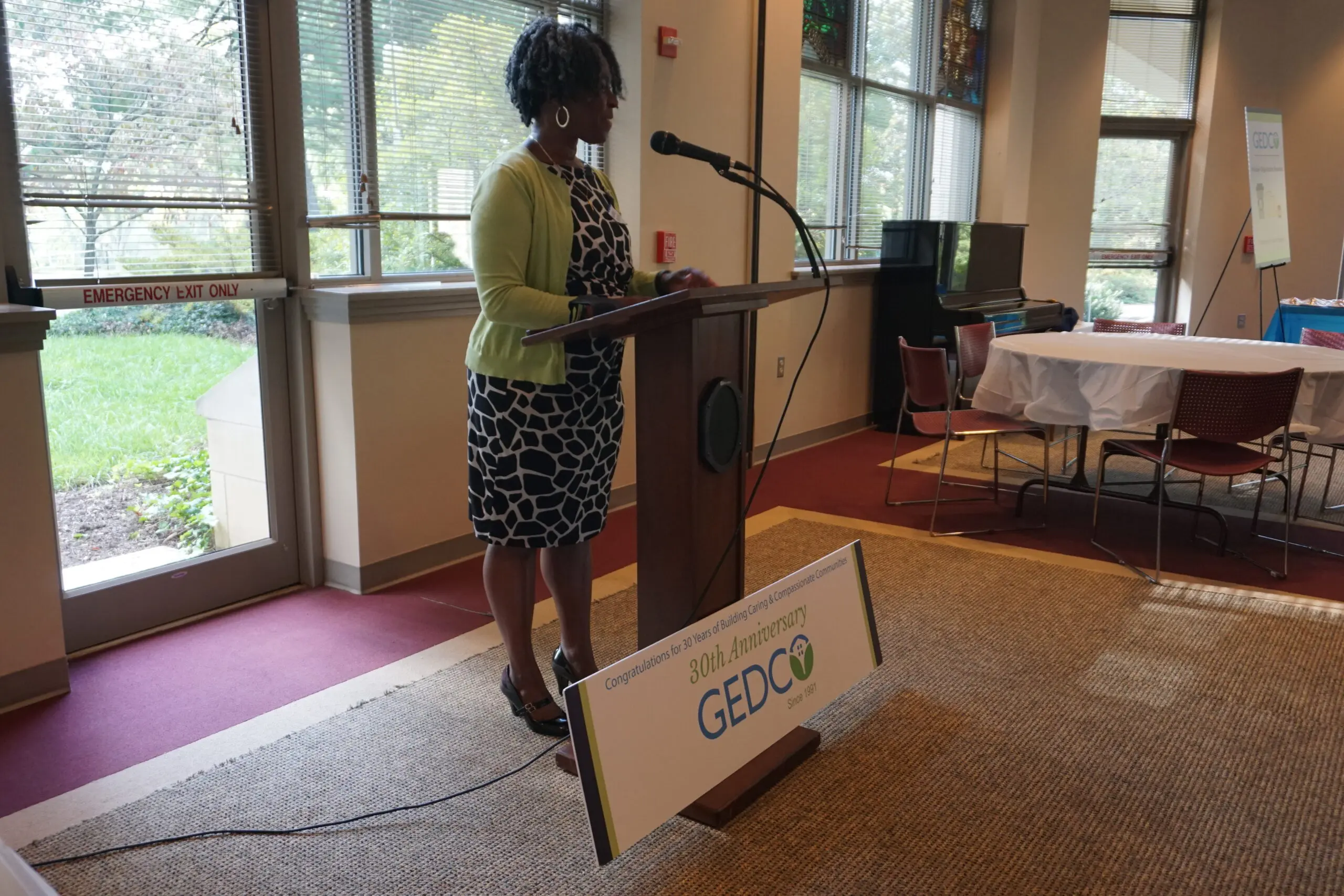 A woman standing at the podium in front of a sign.