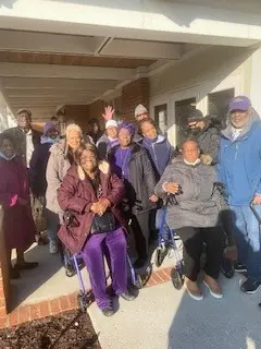 A group of people standing outside in the sun.