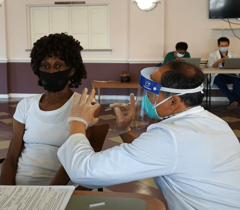 A man wearing a face mask and gloves is sitting next to a woman.