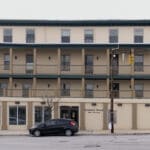 A black car parked in front of an apartment building.