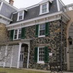 A stone house with green shutters and white trim.